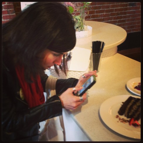 Author Terry Hope Romero photographing the Chocolate Caramel Pistachio Torte at Petunia's Pies & Pastries.